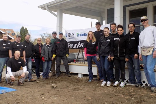 group of men and women in front of banner on house porch that says, "Founder's Day" with The Opus Group and Habitat for Humanity logos